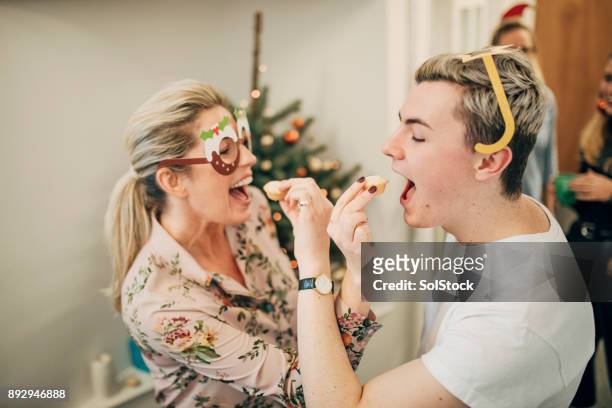 coworkers feeding each other mince pies - party pies imagens e fotografias de stock
