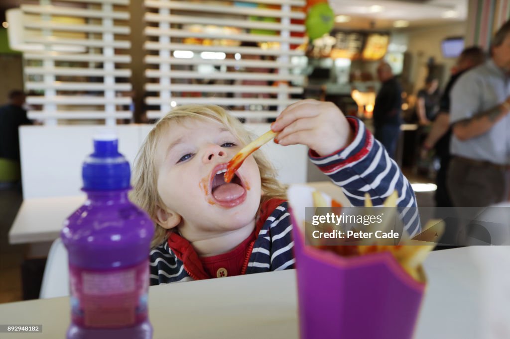 Toddler eating fast food in restaurant