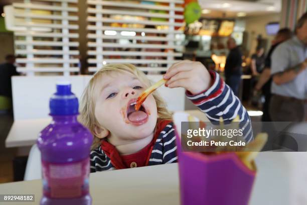 toddler eating fast food in restaurant - fast food french fries - fotografias e filmes do acervo