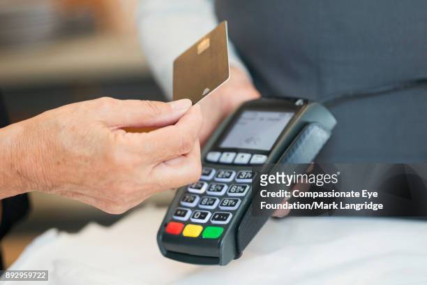 close up of senior woman using contactless payment in shop - クレジットカードリーダ ストックフォトと画像