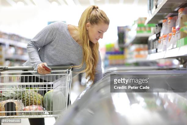 young woman shopping in supermarket - frozen food supermarket stock pictures, royalty-free photos & images