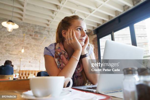 woman looking bored in coffee shop with laptop - student day dreaming stock pictures, royalty-free photos & images