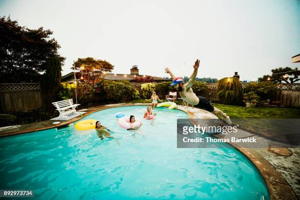 man doing belly flop into backyard pool during party with friends on summer evening - 2017 usa diving summer stock pictures, royalty-free photos & images