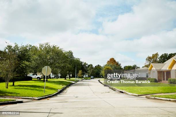 view of street in residential neighborhood on sunny afternoon - quartier résidentiel photos et images de collection