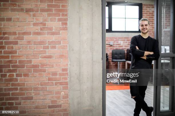 young designer smiling and standing at the door of his office. vanguardian startup in the technology industry. millennial. real life. real people. - graphic design studio stock pictures, royalty-free photos & images