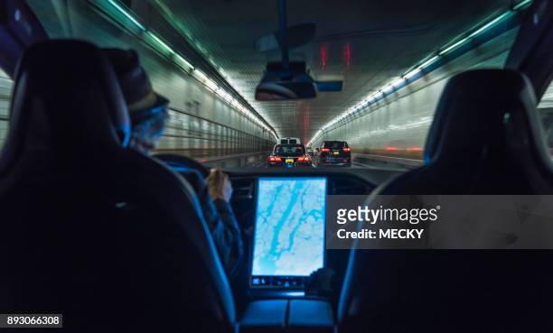 man driving electric vehicle through holland tunnel - tesla interior stock pictures, royalty-free photos & images