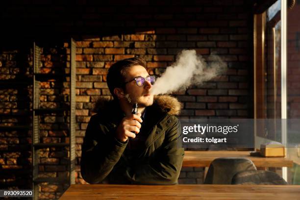 the man smoke an electronic cigarette at the cafe - electronic vapor stock pictures, royalty-free photos & images