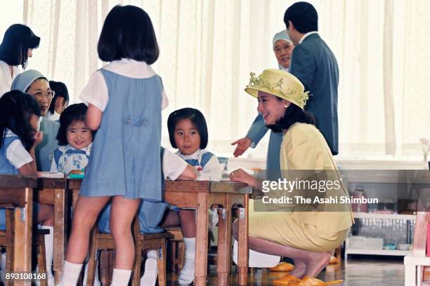 Crown Prince Naruhito and Crown Princess Masako talk to children during their visit to Moroioka Shirayuri Gakuen on July 14, 1993 in Morioka, Iwate,...