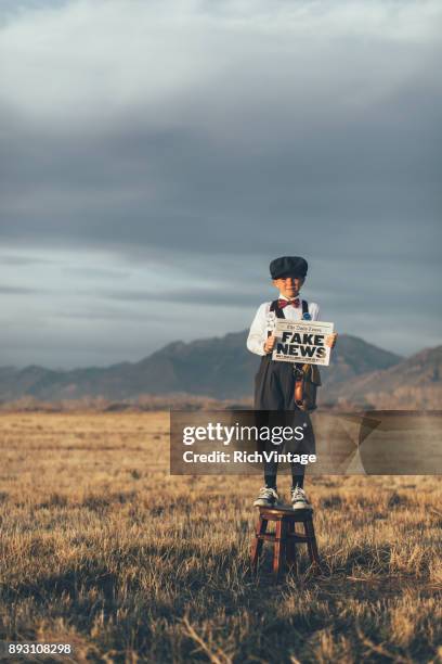 old fashioned news boy holding gefälschte zeitung - pressemitteilung stock-fotos und bilder