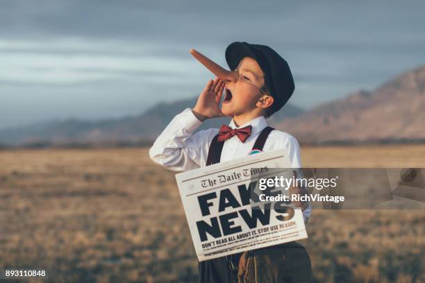 old fashioned pinocchio news boy holding gefälschte zeitung - sneaking stock-fotos und bilder