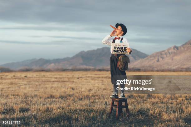 old fashioned pinocchio news boy holding fake newspaper - newspaper boy stock pictures, royalty-free photos & images