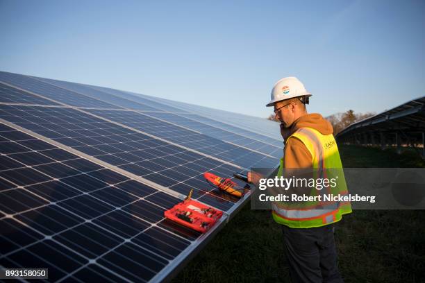 Employees from a Radian Generation's operations and maintenance team change out a faulty solar inverter along a row of solar panels December 4, 2017...