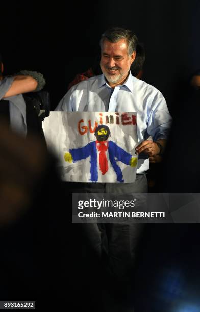 The Chilean presidential candidate for the ruling New Majority coalition, Alejandro Guillier, holds up a child's drawing during his final election...