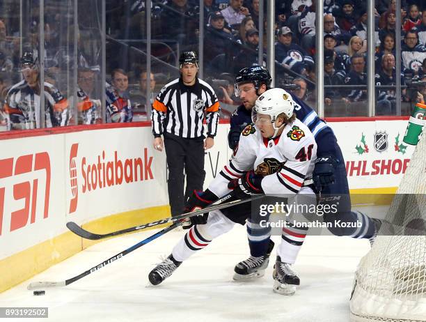 John Hayden of the Chicago Blackhawks plays the puck away from Tucker Poolman of the Winnipeg Jets during first period action at the Bell MTS Place...