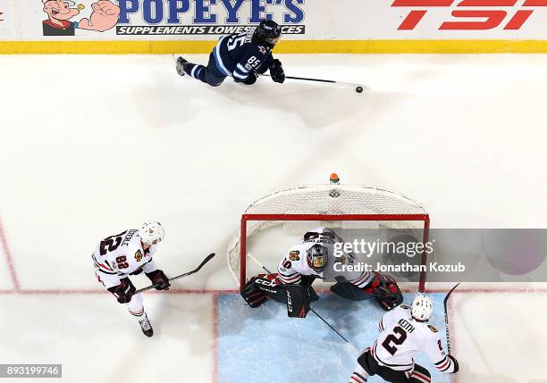 Mathieu Perreault of the Winnipeg Jets plays the puck behind the net as Jordan Oesterle, goaltender Corey Crawford and Duncan Keith of the Chicago...