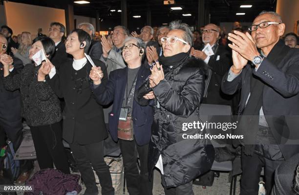 Survivors of the 1945 U.S. Atomic bombings in Japan join others in a round of applause as they watch a broadcast of the Nobel Peace Prize award...