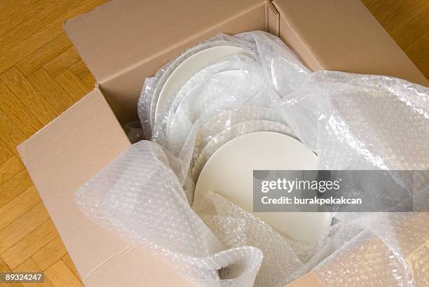 white plates wrapped in bubble wrap stacked in a moving box  - breekbaarheid stockfoto's en -beelden