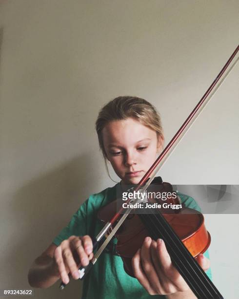 Young girl concentrating while practicing the violin at home