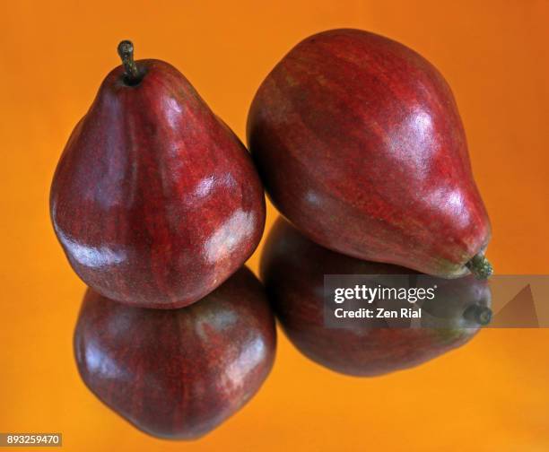 two ripe red bartlett pears against orange background - bartlett illinois stock pictures, royalty-free photos & images