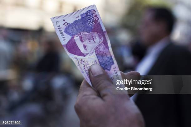 Roadside money changer holds up a Pakistani Fifty Rupee banknotes attempting to attract customers at a currency exchange market in Karachi, Pakistan,...