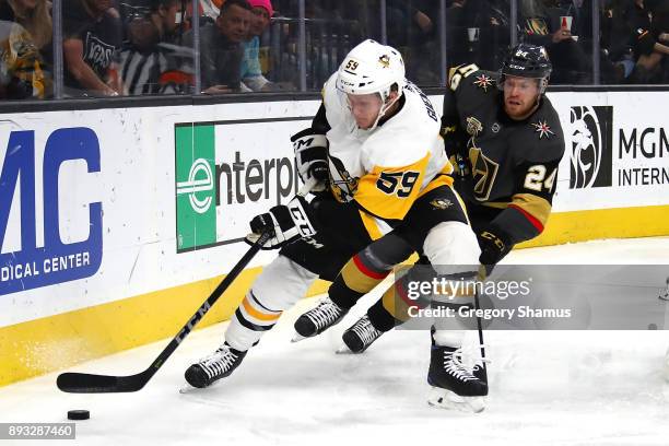 Jake Guentzel of the Pittsburgh Penguins tries to control the puck in front of Oscar Lindberg of the Vegas Golden Knights during the third period at...