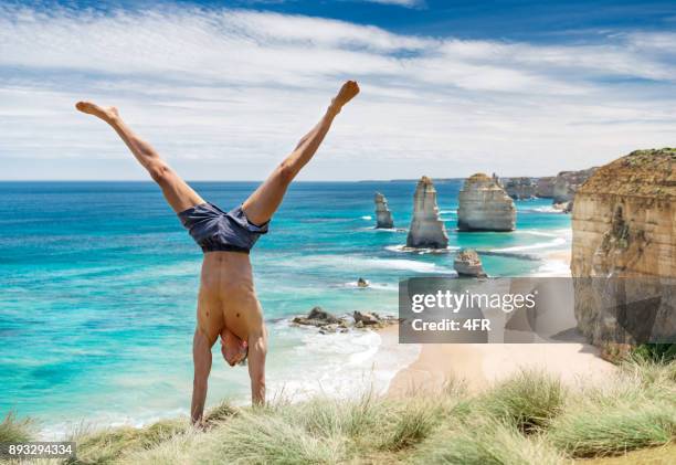tourist doing a handstand in front of the famous twelve apostles, great ocean road, australia - great ocean road stock pictures, royalty-free photos & images