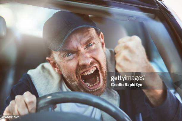 enfurecido hombre sacudiendo el puño a través de parabrisas: rabia del camino - locura fotografías e imágenes de stock