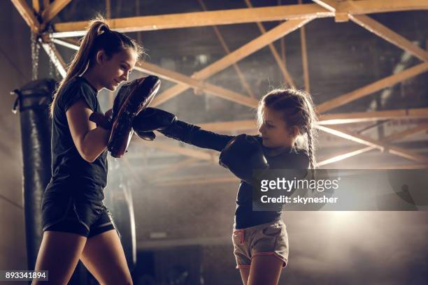 kleines mädchen üben boxen mit ihrem trainer im fitnessstudio. - verteidigen stock-fotos und bilder
