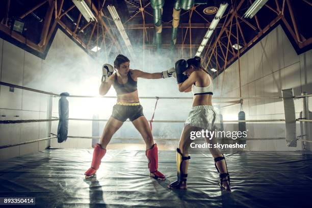 longitud total de dos mujeres duelo en un combate de boxeo en el club de salud. - muay thai fotografías e imágenes de stock