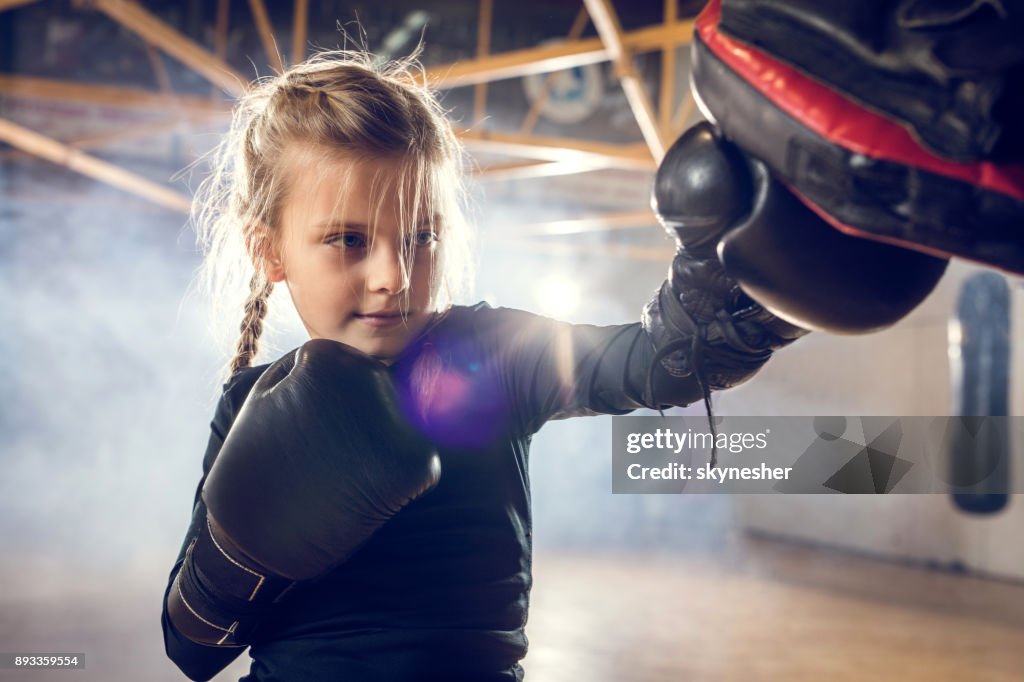 Small boxer exercising punches on a sports training in a gym.