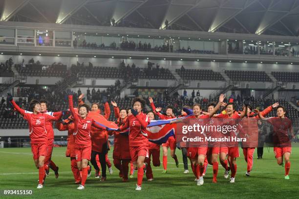 North Korean players run toward supporters with waving a giant national flag as they cerebrate the East Asian Champions at the award ceremony...