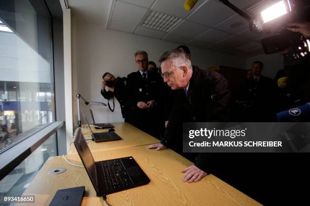 German Interior Minister Thomas de Maiziere looks at a computer running an automatic facial recognition system during a visit at the Suedkreuz train...