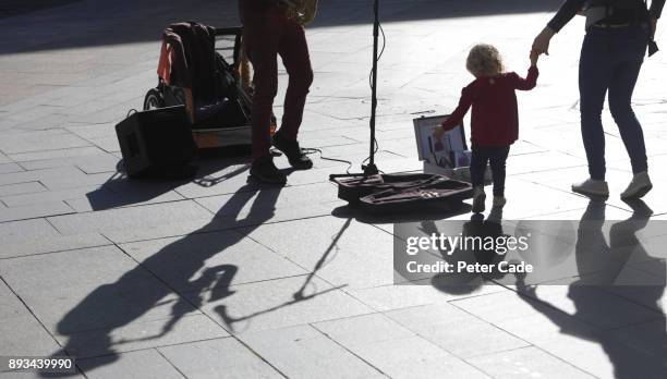 toddler putting change into buskers guitar case - street artist - fotografias e filmes do acervo