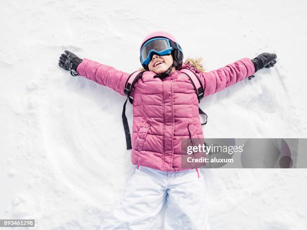 kleines mädchen lachten und spielten schnee-engel - kids ski stock-fotos und bilder
