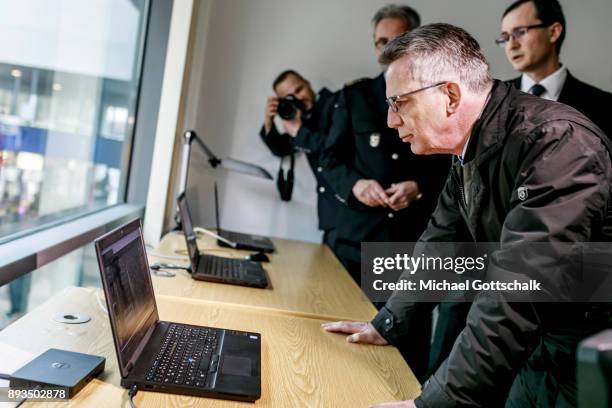 German Interior Minister Thomas de Maiziere inspects three computers with different monitoring systems during his visit to a project for automatic...