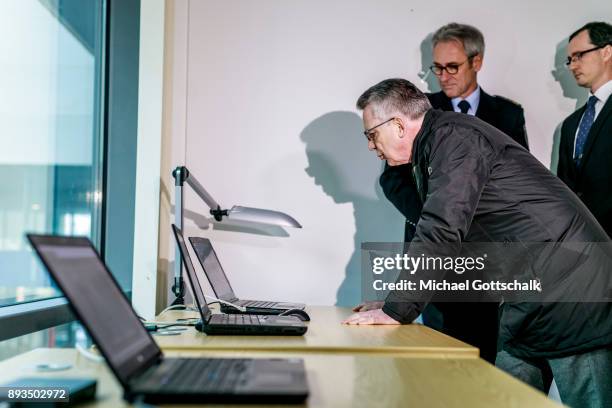 German Interior Minister Thomas de Maiziere inspects three computers with different monitoring systems during his visit to a project for automatic...