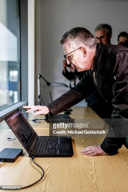 German Interior Minister Thomas de Maiziere inspects three computers with different monitoring systems during his visit to a project for automatic...