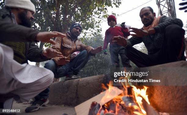 People warm themselves by a bonfire on a cold winter morning, on December 15, 2017 in New Delhi, India. Expect a further dip in temperature as cold...