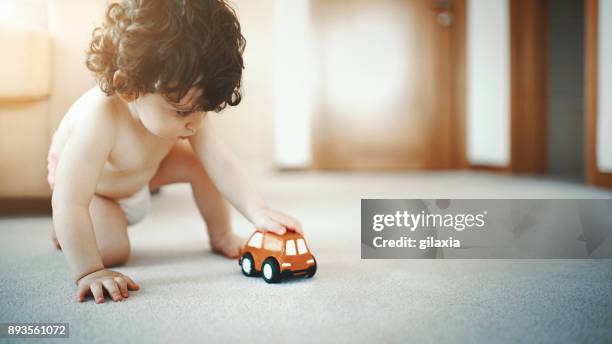 niño jugando con un carrito de juguete. - diaper boy fotografías e imágenes de stock