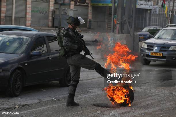 Israeli security forces kicks a burning tyre as Palestinians gather to stage a protest against U.S. President Donald Trumps announcement to recognize...