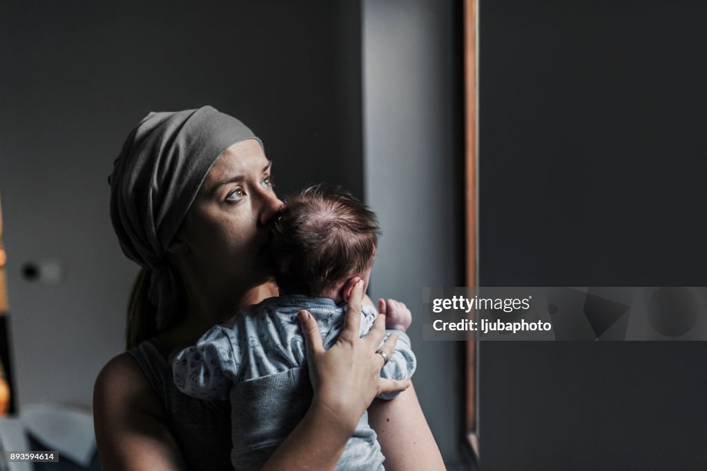 Photo de femme pensive, regardant par la fenêtre tout en tenant son fils