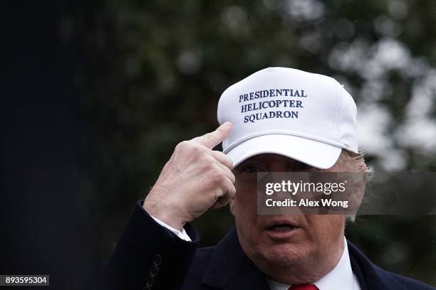 President Donald Trump points to his cap as he walks on the South Lawn after he returned to the White House December 15, 2017 in Washington, DC....