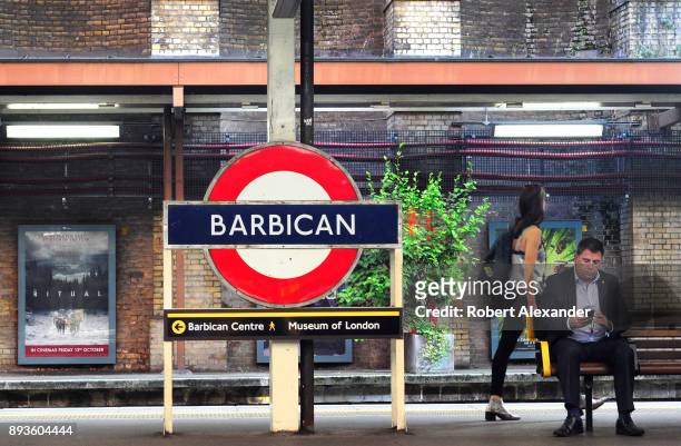 Man waiting for a train at the Barbican underground station uses his smartphone as he waits on the platform in London, England.
