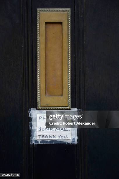 Handmade notice taped to a front door near a mail slot asks the postman to refrain from delivering 'junk mail' to a home in London, England.