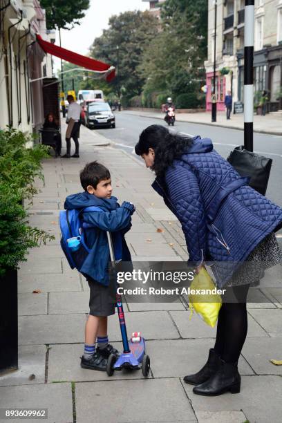 Boy with a push scooter gets a stern talking from his mother on a sidewalk in the Belgravia district of London, England.