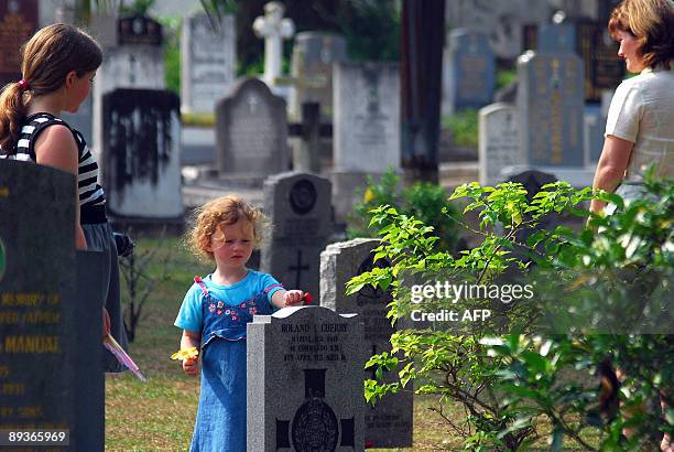 Asia-WWII-history-cemeteries BY ROMEN BOSE A picture dated June 11, 2009 shows a girl placing a flower on a tombstone of a WWII victim at Kamunting...