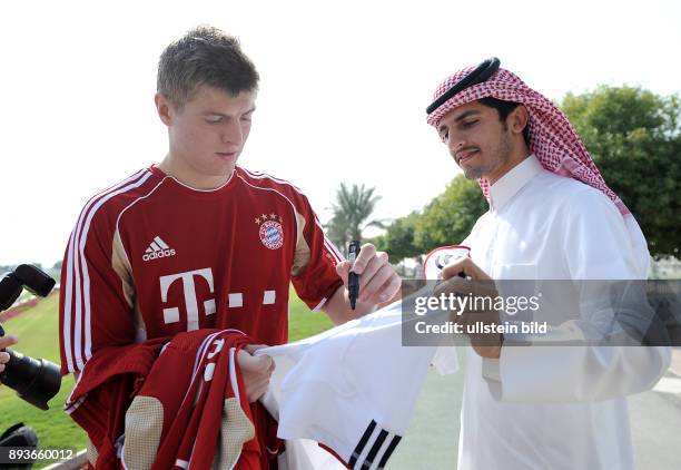 Wintertrainingslager des FC Bayern Muenchen. Toni Kroos schreibt fuer einen katarischen FC Bayern Fan ein Autogramm auf ein FC Bayern Trikot.