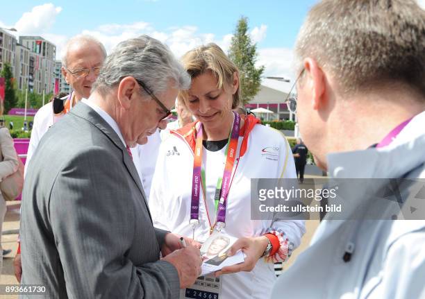 Olympia 2012 London Bundespraesident Joachim Gauck gibt bei einem Besuch im Olympischen Dorf ein Autogramm.