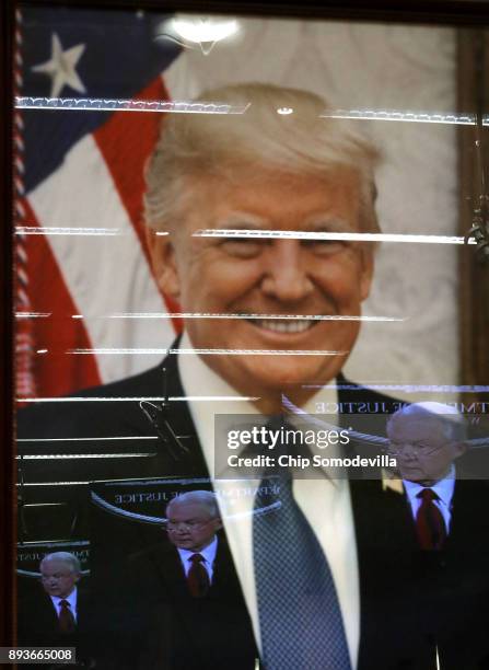 Attorney General Jeff Sessions' television image is reflected in President Donald Trump's official portrait during a news conference at the...