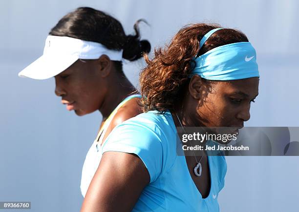 Venus Williams and Serena Williams look on during their doubles match against Yi Chen of Taipei and Mashona Washington during the Bank of the West...